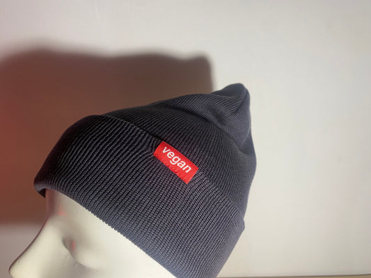 Grey beanie with a red 'vegan' label on a mannequin head against a neutral background