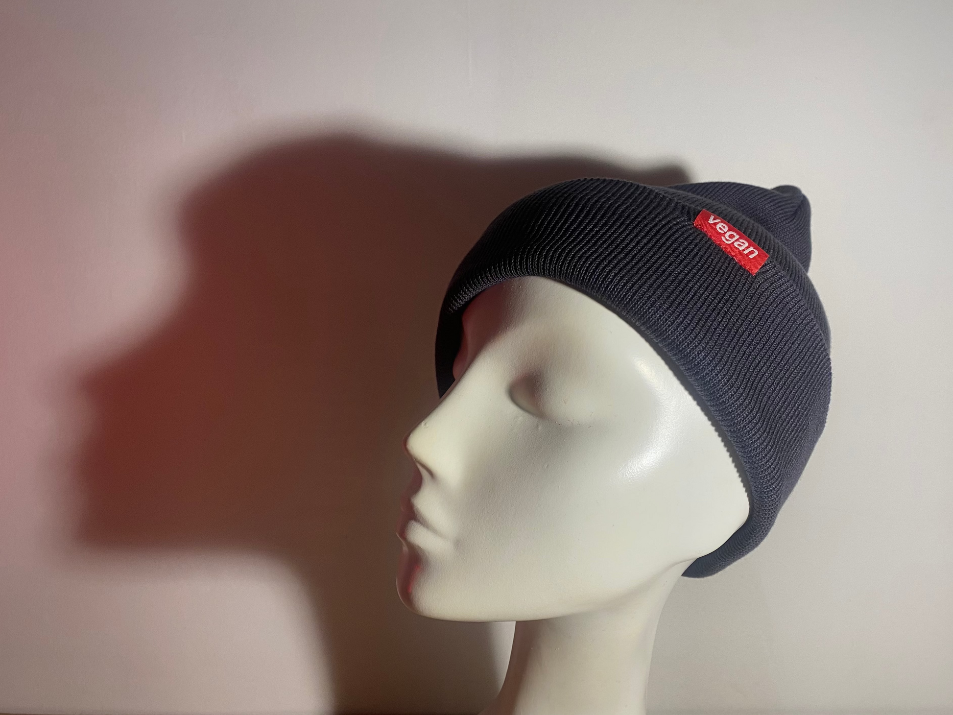 Grey beanie with a red label on a mannequin head against a plain background