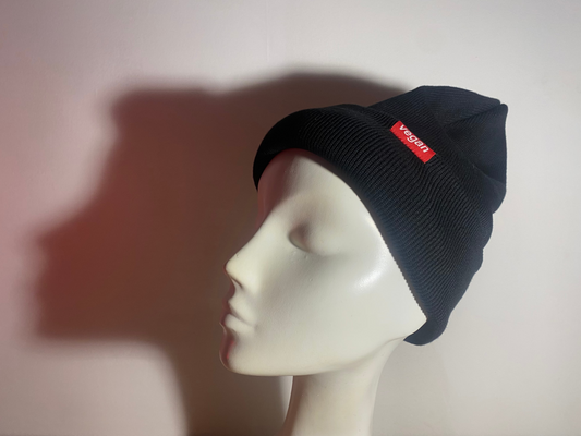 Black beanie with a red label on a mannequin head against a plain background